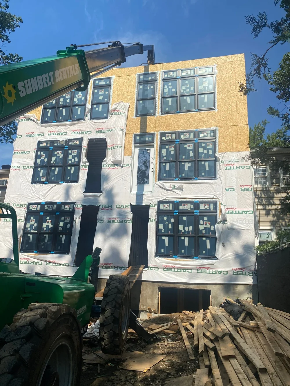Multifamily building mid-renovation with new windows and exterior sheathing, a Washington, DC project by CS1 Construction.